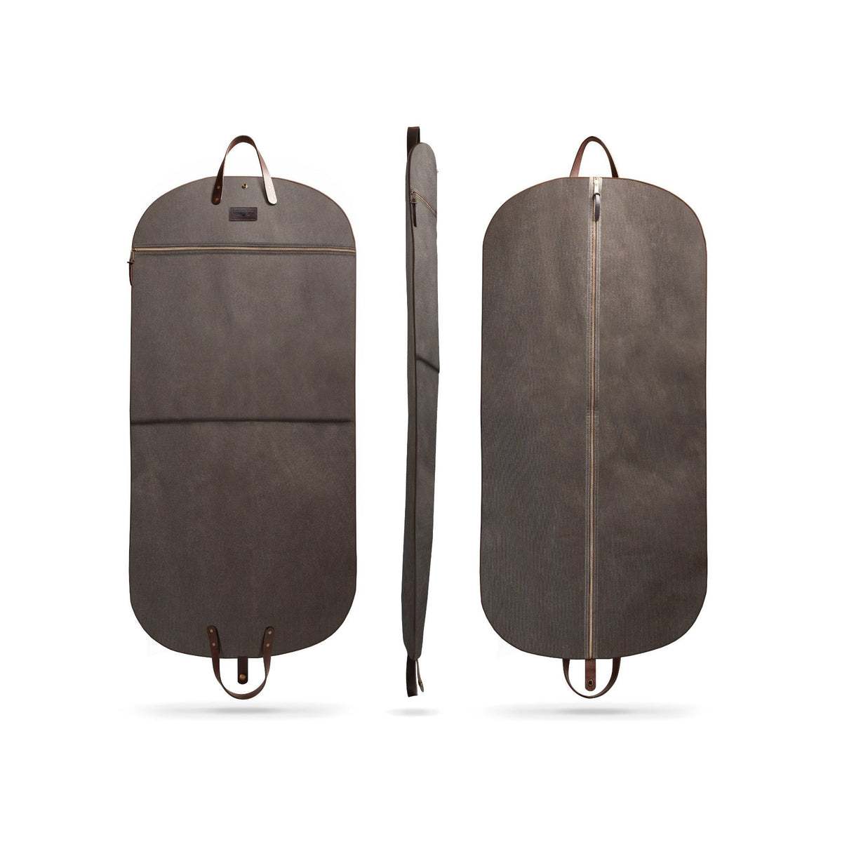 A dark brown wax duck canvas garment bag shown from three angles: front, side, and back. The bag features a zippered main compartment, a front zippered pocket, leather handles, and leather loops at the bottom, displayed on a clean white background.