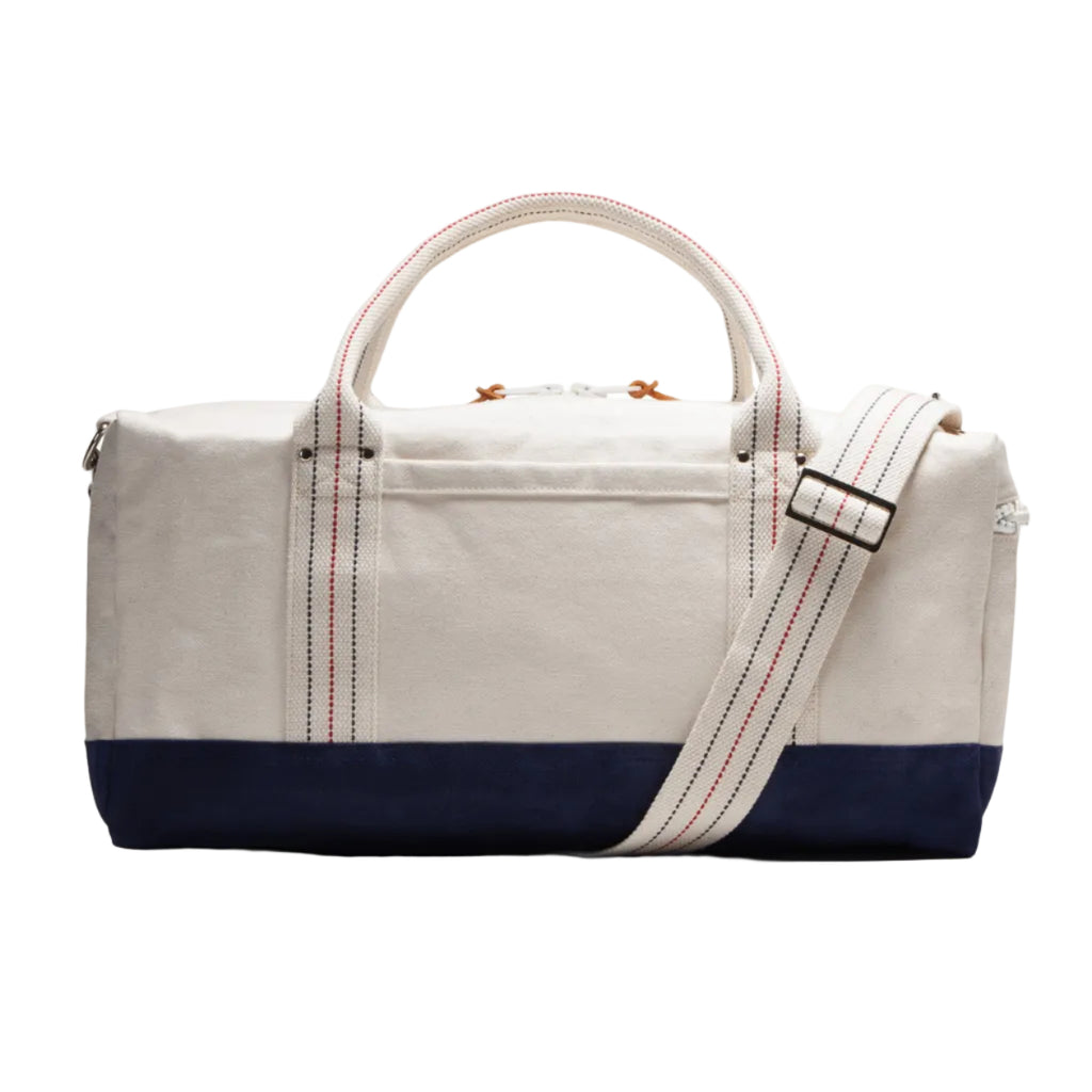White and navy duffel bag with a strap on a white background