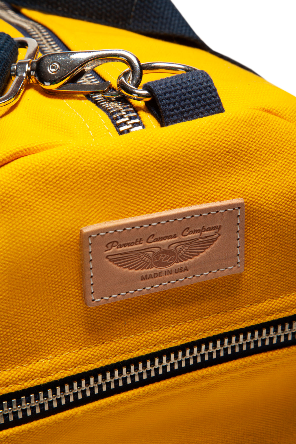 Yellow backpack with a leather patch and keychain on a white background