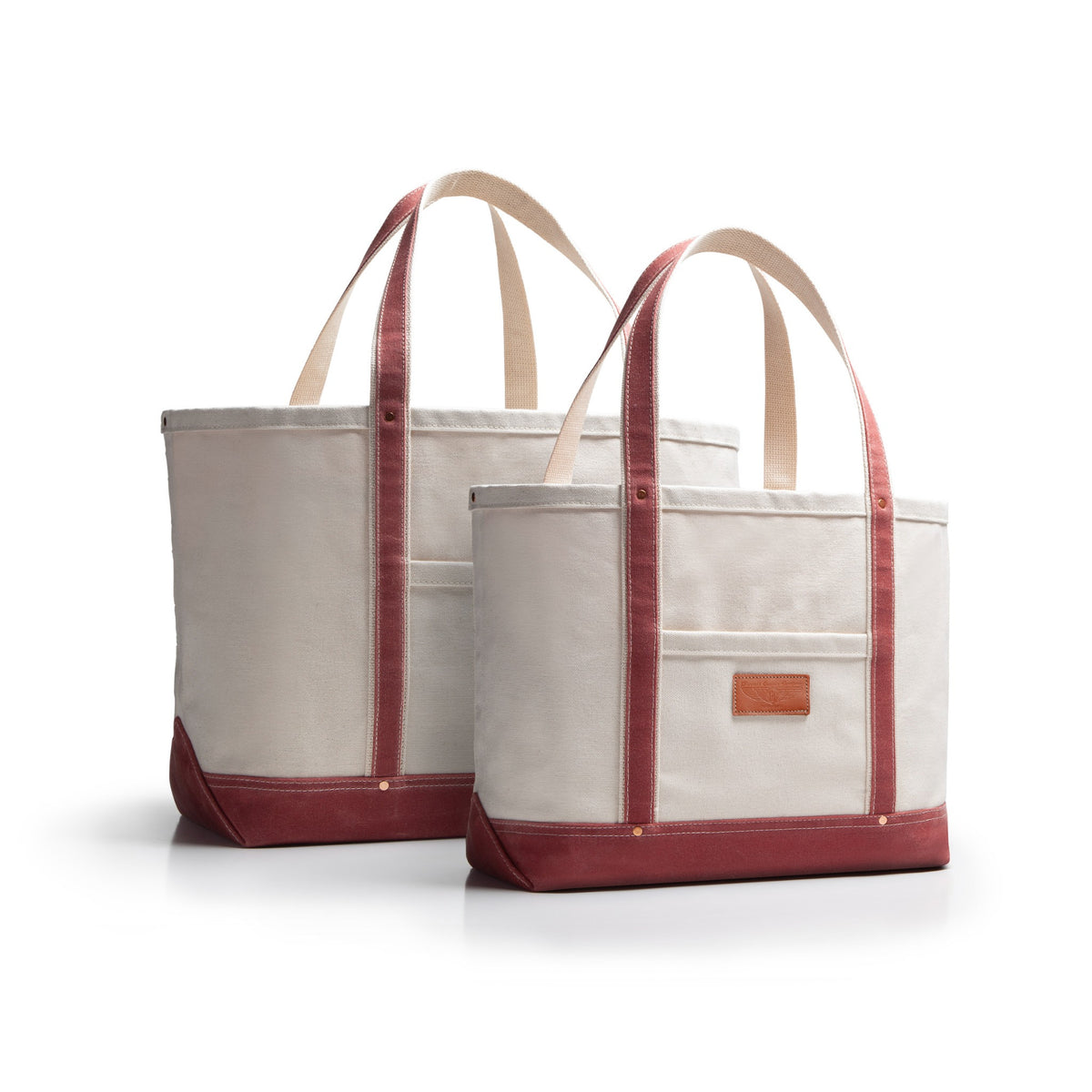 Two duck canvas canvas tote bags with cream bodies and dark red trim, displayed on a clean white background.