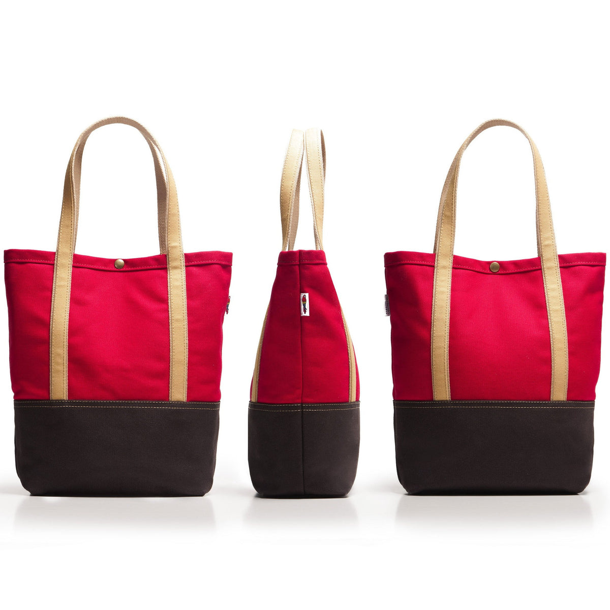 Three views of a canvas tote bag on a white background, showing the front, side, and back. The bag features a bright red upper body, a dark brown bottom base, and light beige handles.
