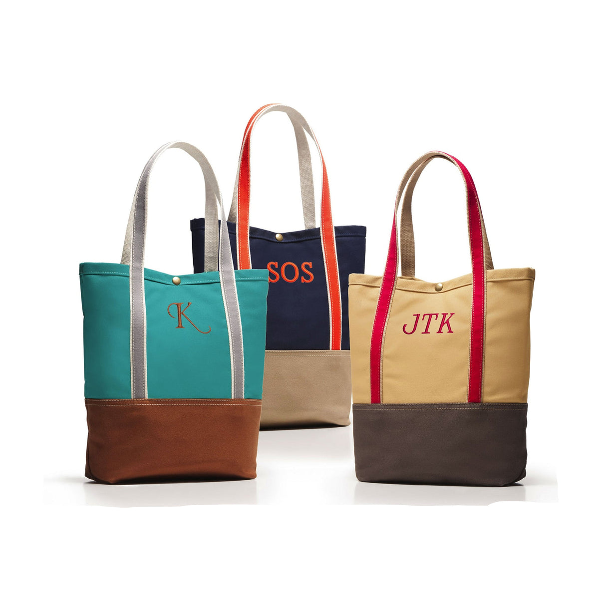Three canvas tote bags with monogrammed initials are displayed on a white background. The front-left bag is teal and brown with light gray handles.