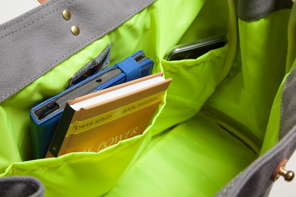 Green inside of grey bag with books and a blue device inside