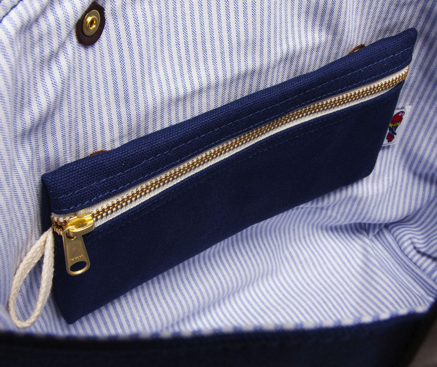Navy pouch with gold zipper on a blue and white striped fabric background