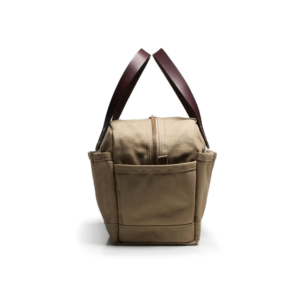 Beige tote bag with brown leather handles on a white background
