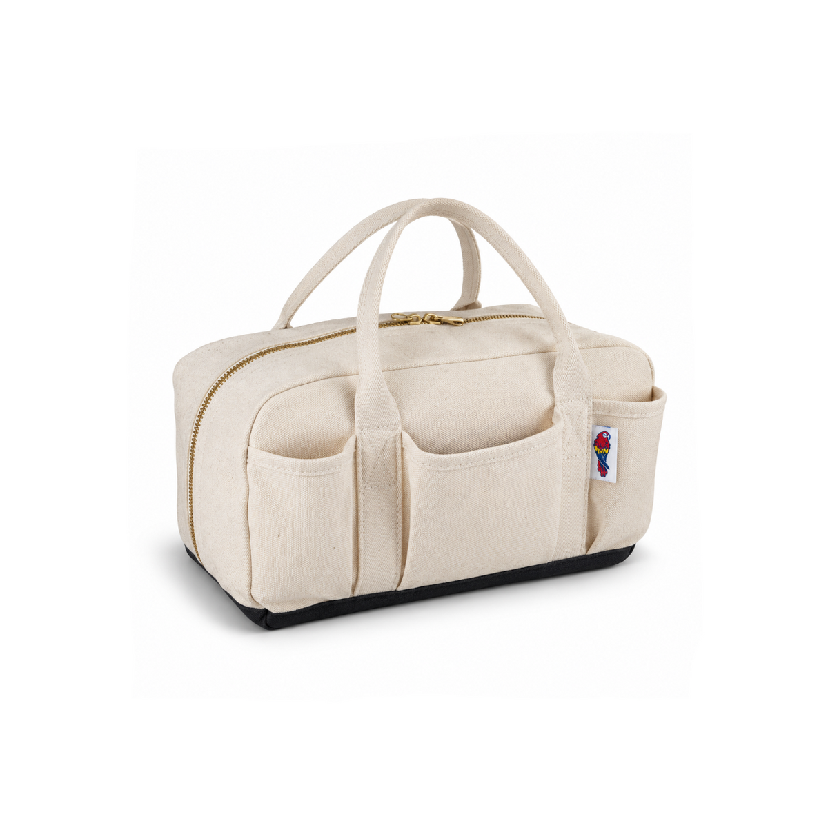 A cream-colored canvas travel organizer bag with gold-tone zippers, dual top handles, and a side pocket featuring a colorful bird patch, set against a plain white background.