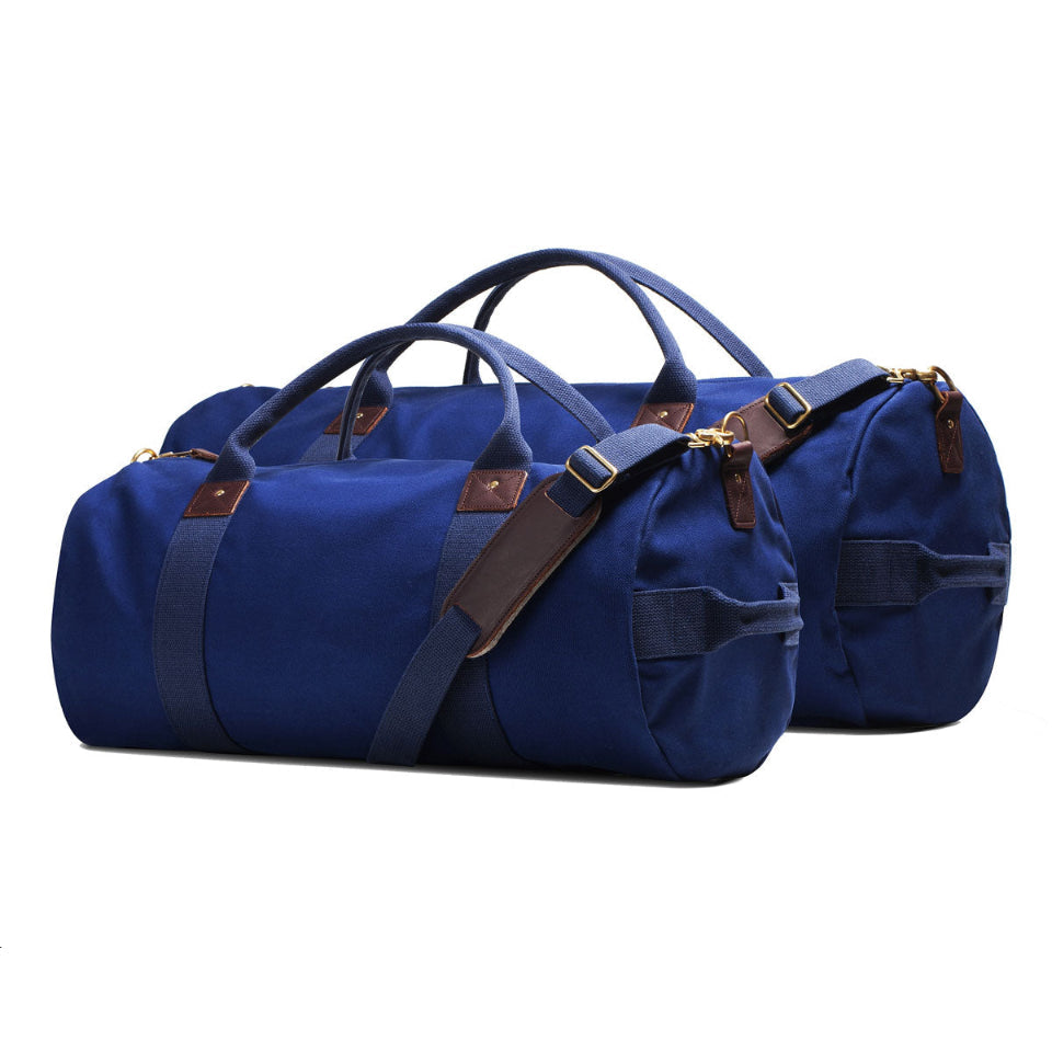Two blue duffel bags with brown straps on a white background