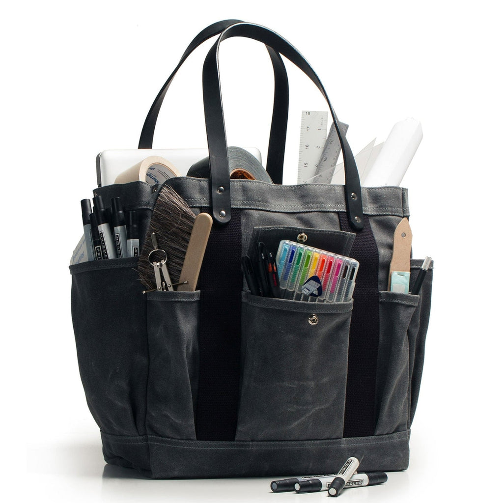 Black tote bag with various stationery items on a white background